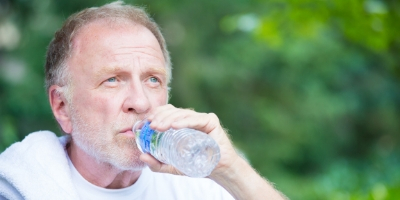 older man outside drinking water