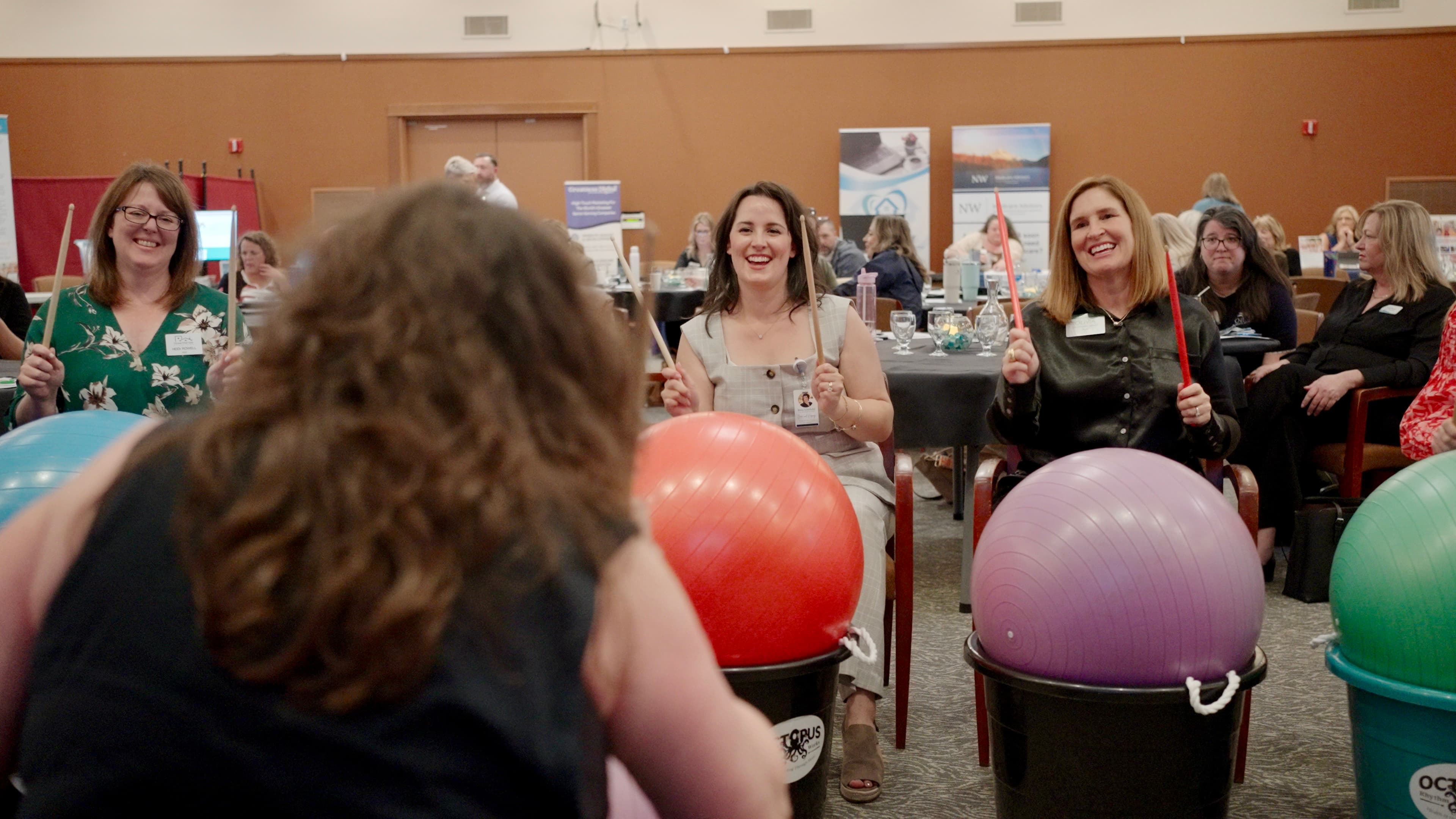 Conference attendees enjoying a team-building drum exercise with colorful exercise balls